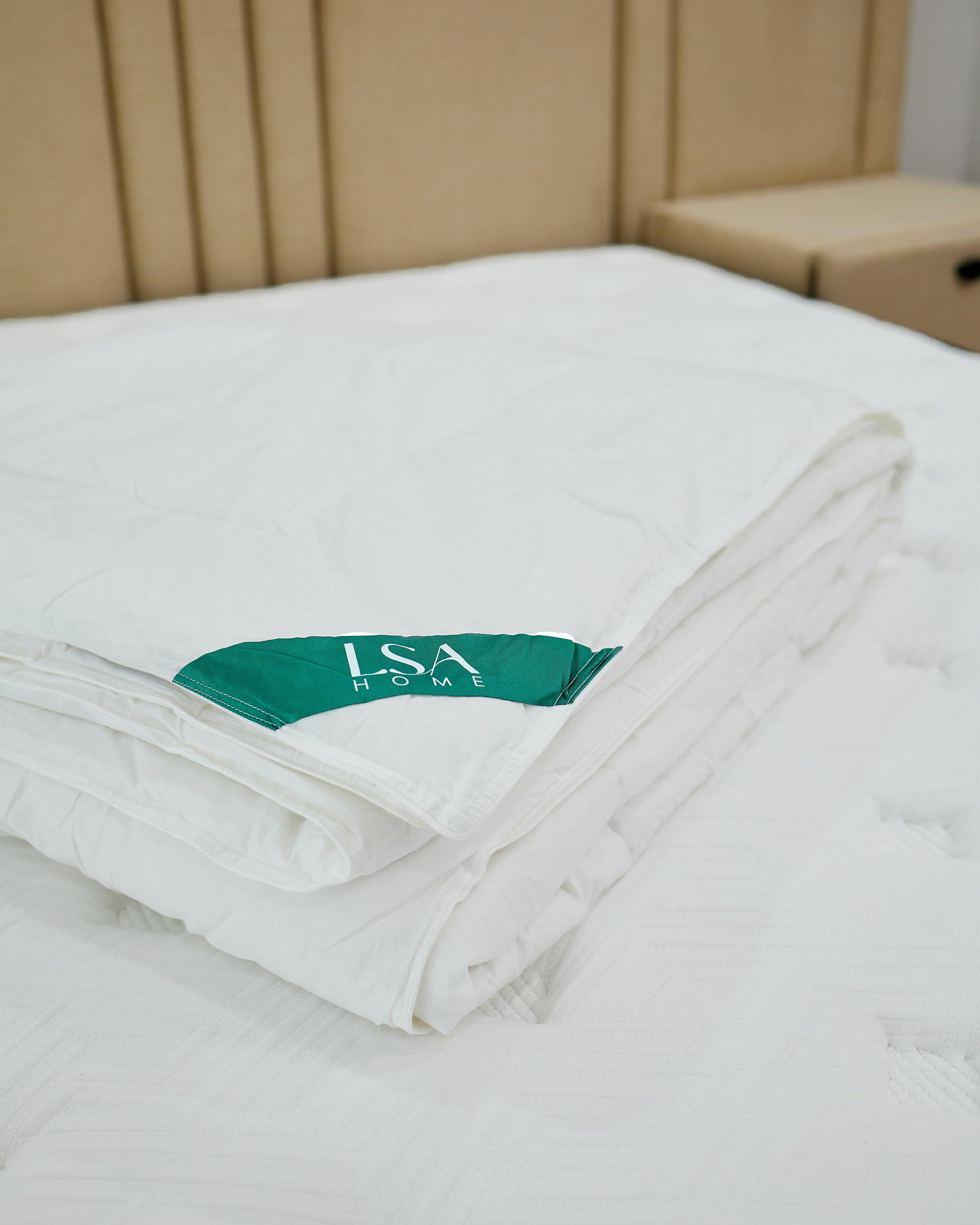 Lightweight down alternative duvet folded on bed with green ISA Home label