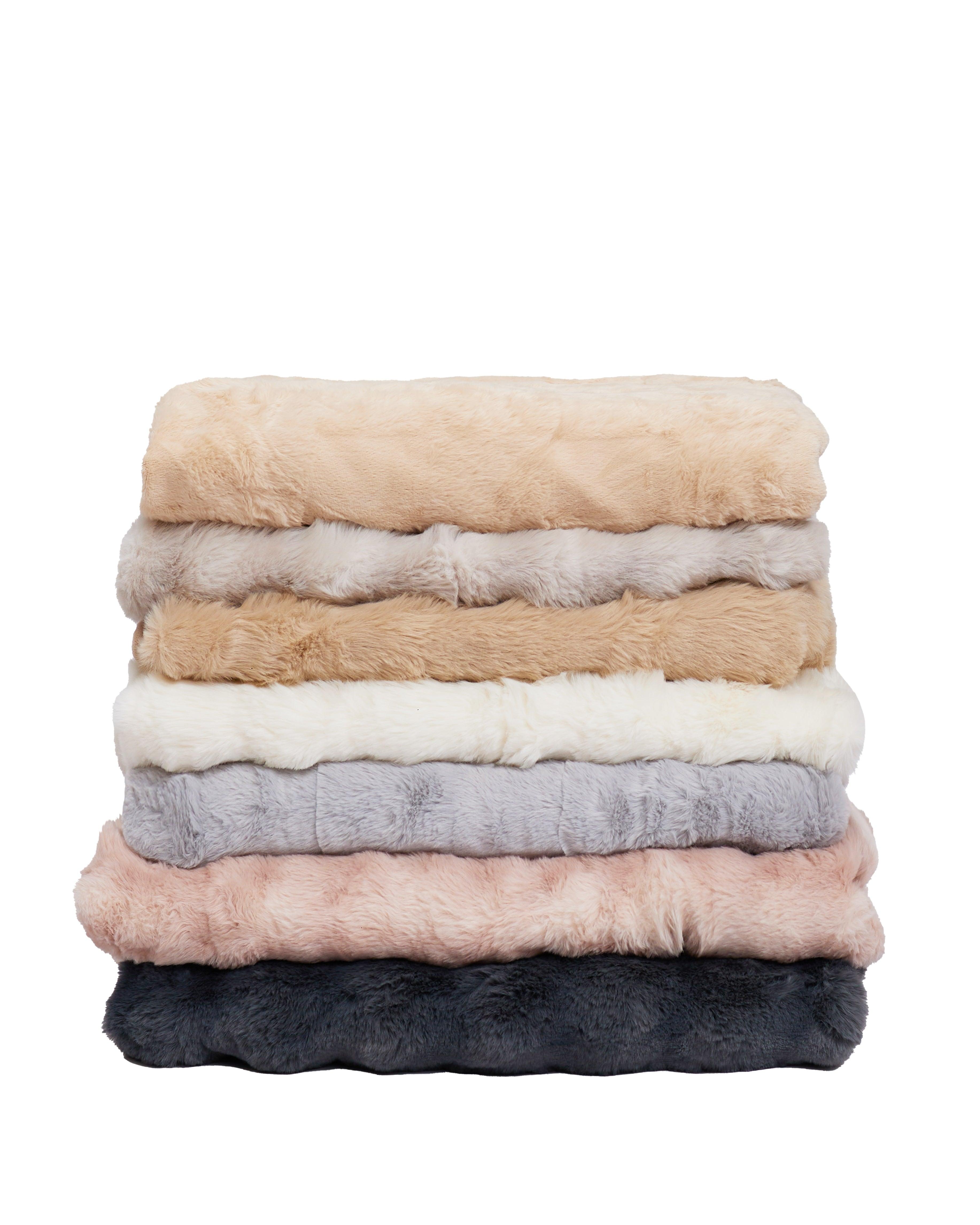 Stack of soft and fluffy Amelia throw blankets in various neutral colors for cozy home decor and extra warmth