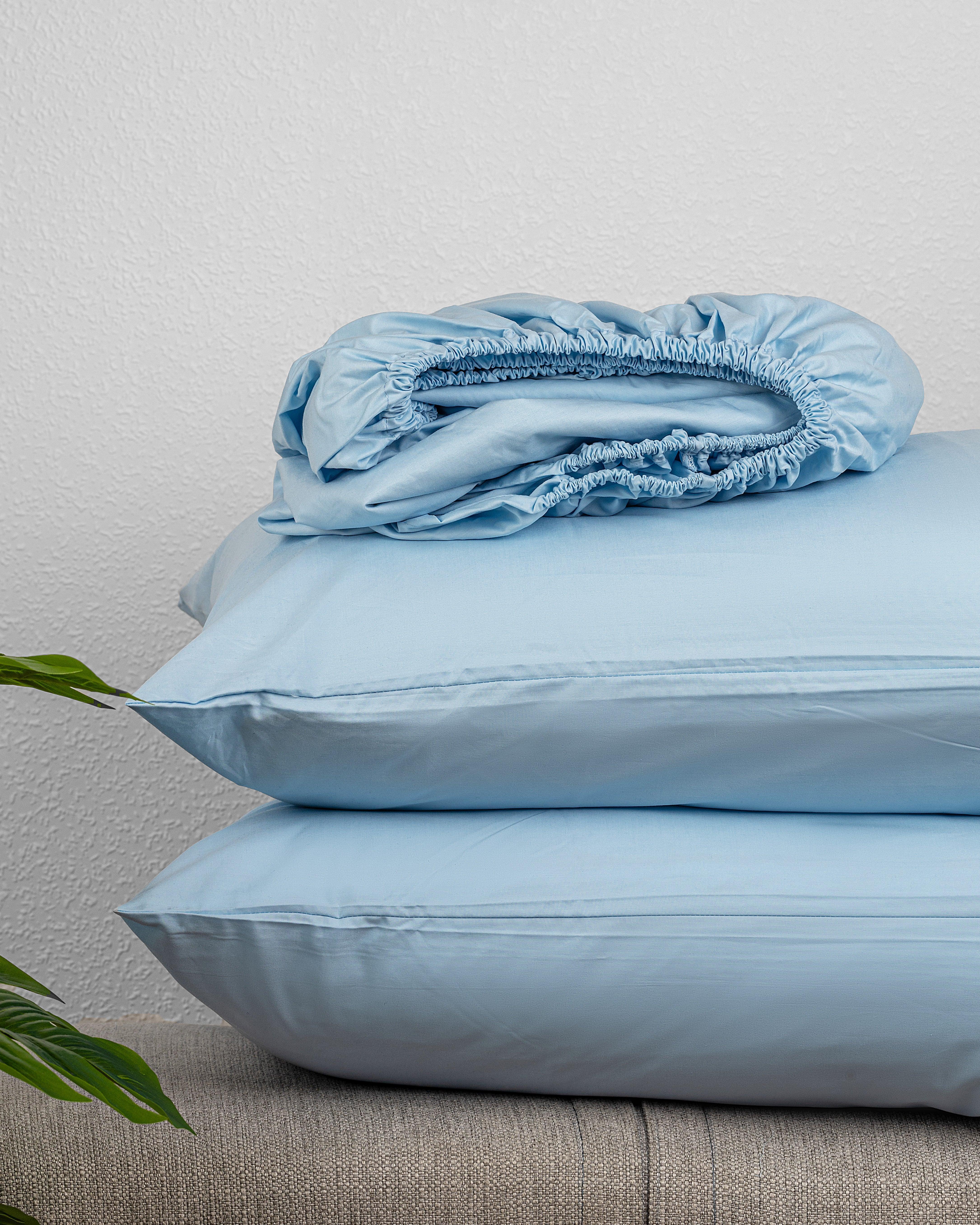 Regal Collection Fitted Sheet Set in soft cotton, stacked on a sofa.