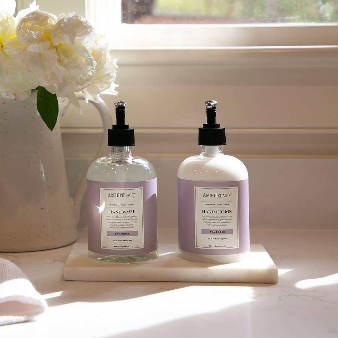 Archipelago Lavender Hand Wash and Lotion Set on countertop with flowers.