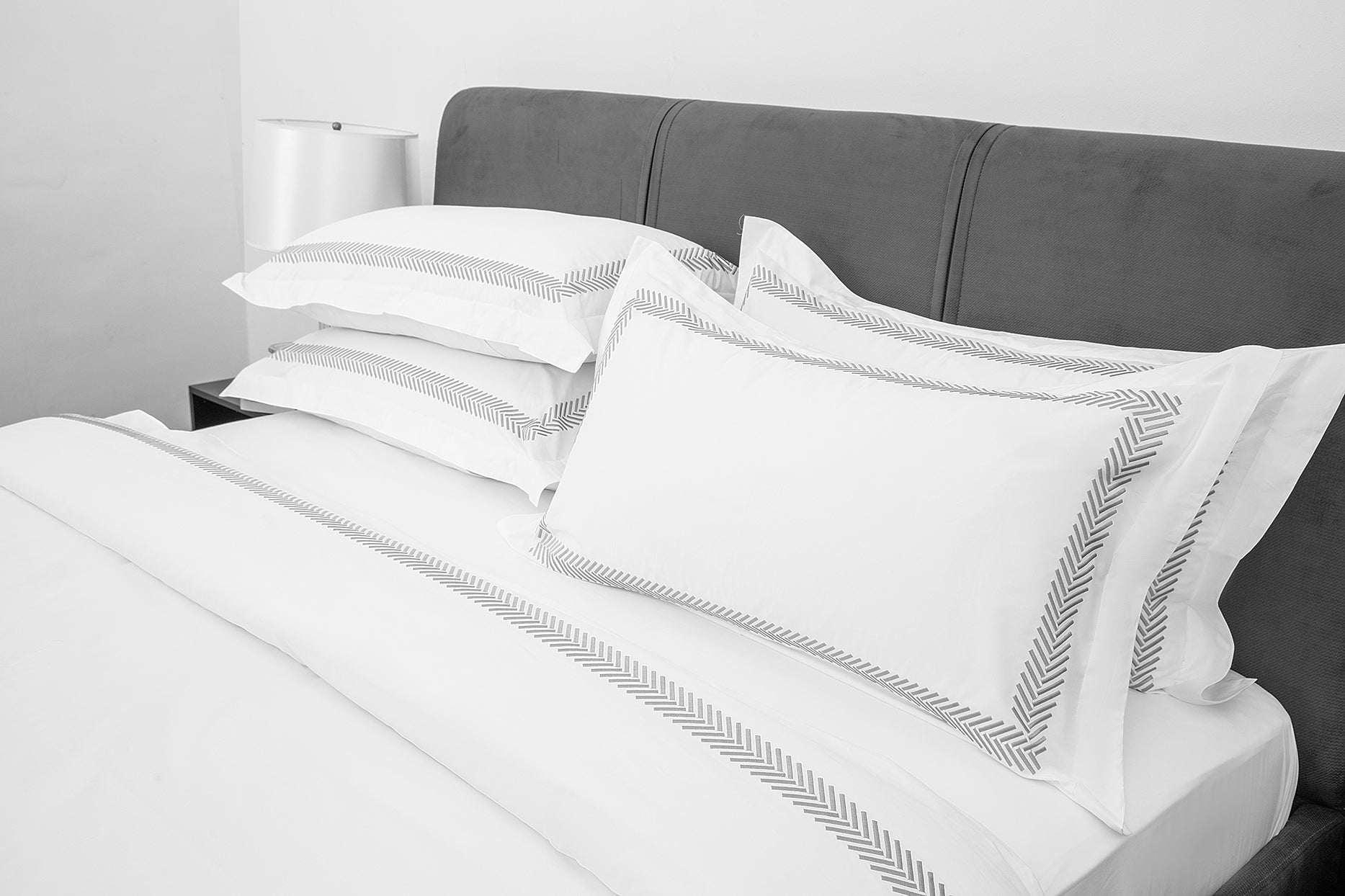 Chevron Luxury White 6pc Bedding Set with embroidered detailing on a bed.