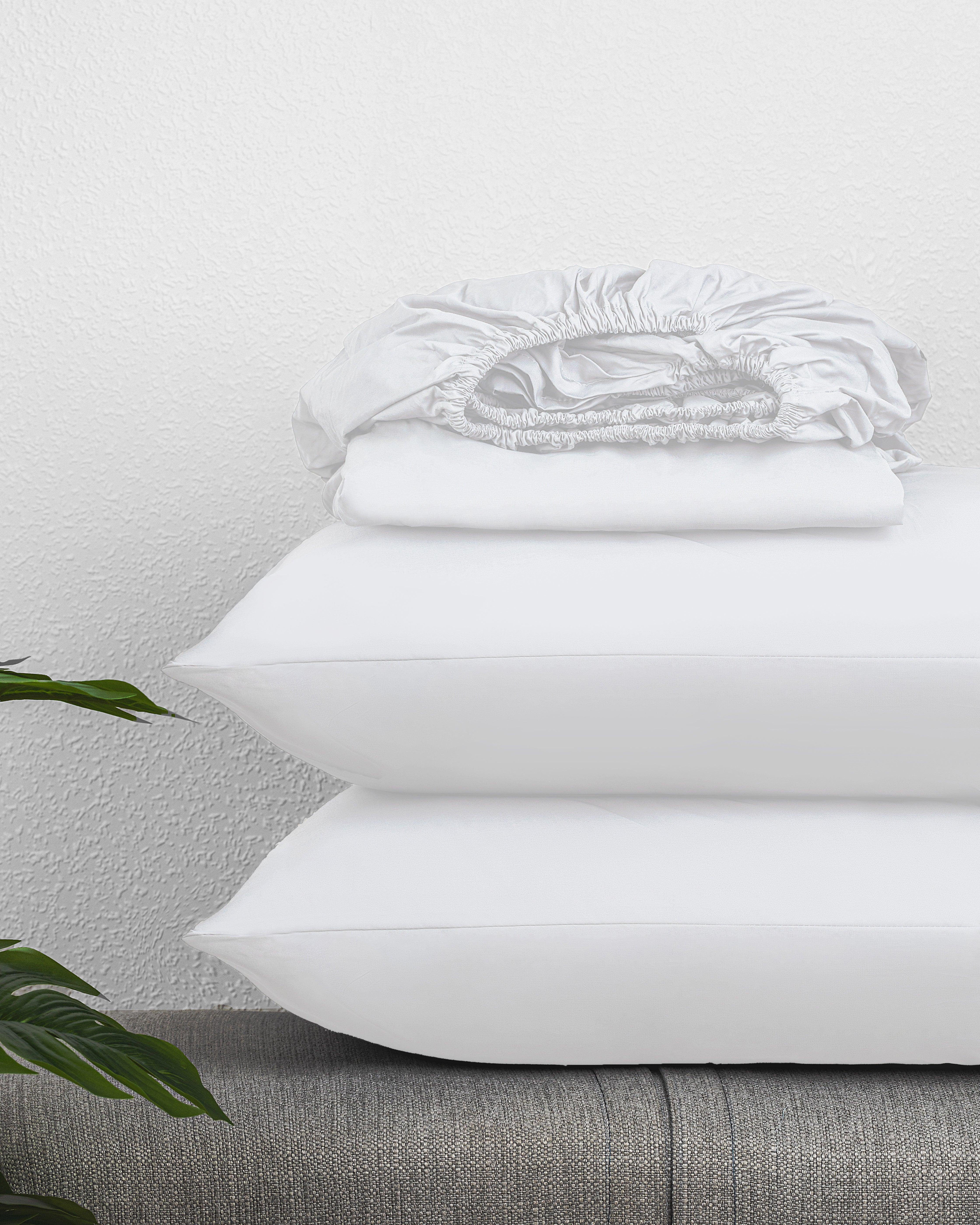 Regal Collection Fitted Sheet set folded on top of white pillows on a gray bed frame