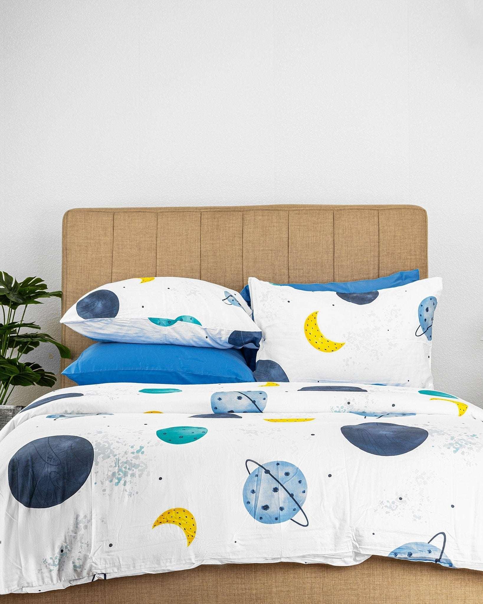 Kids bedding set with galaxy print featuring planets, moons, and stars on white duvet cover and pillowcases