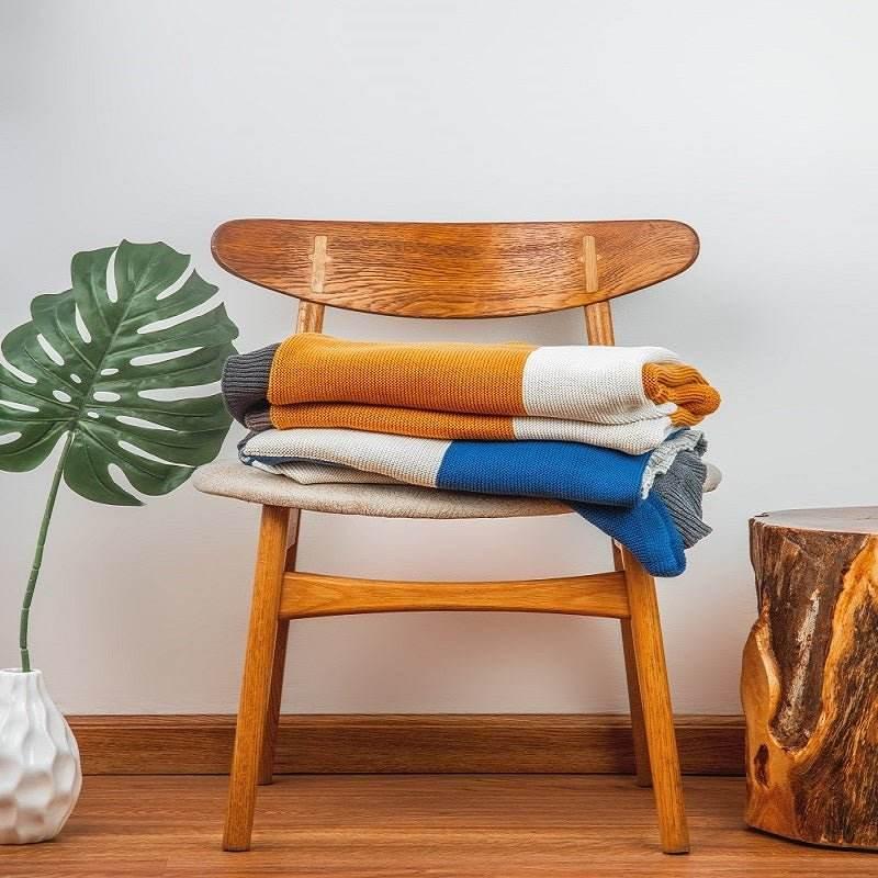 Folded Rayna Throw with ombre design in vibrant colors on a wooden chair in a cozy living space